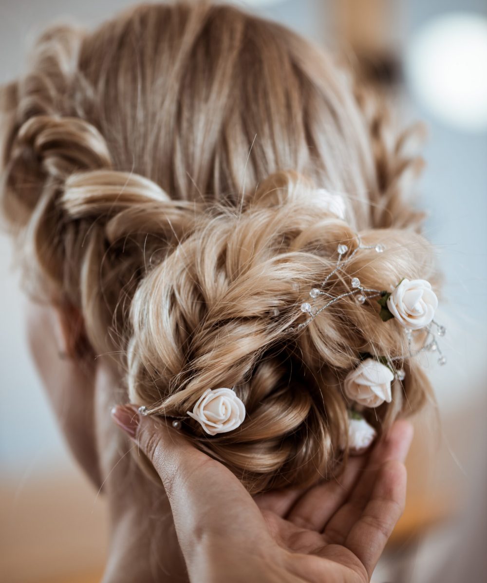 Female hairdresser making hairstyle to beautiful blonde girl in beauty salon. Copy space.